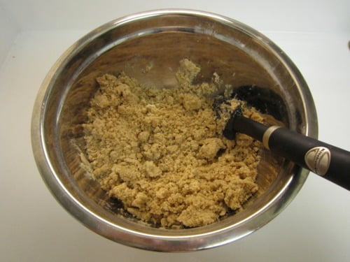 Crumb topping mixture being prepared in a stainless steel bowl with a spatula for crumb cake.