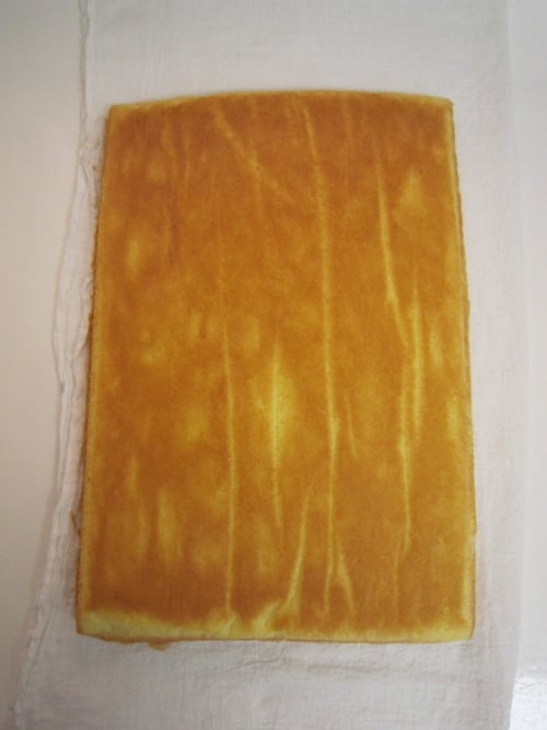 Baked sponge cake layer placed on a white kitchen towel, prepared for assembling a strawberry torte.