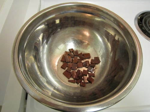 Chopped chocolate pieces in a metal mixing bowl, ready for making chocolate macaroons.