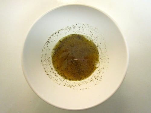 Spice and oil marinade mixture in a white bowl on a white surface.