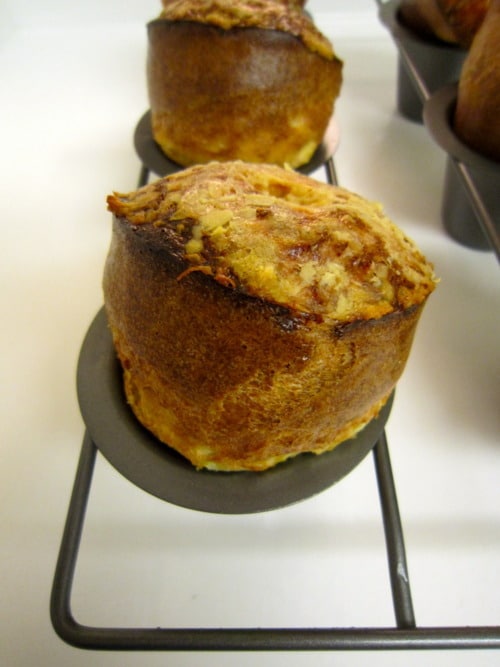 Freshly baked Gruyère popovers in a popover pan, golden brown with a crisp exterior.