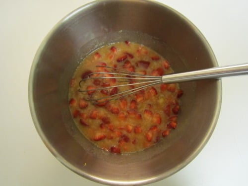 Chopped strawberries mixed into a wet batter in a stainless steel bowl with a whisk for strawberry banana blueberry lemon muffins.