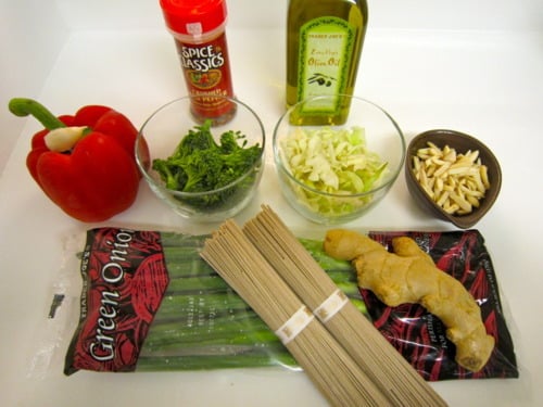 Ingredients for soba noodle stir-fry with spicy almond butter sauce, including red bell pepper, green onions, broccoli, cabbage, olive oil, slivered almonds, ginger, crushed red pepper, and soba noodles.
