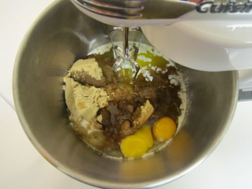 Brown sugar, eggs, butter, and vanilla extract in a mixing bowl with a hand mixer, ready to be blended for strawberry white chocolate macadamia nut cookies.