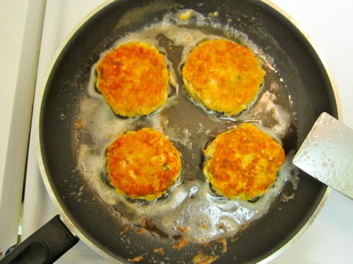 Golden-brown salmon cakes frying in a skillet.
