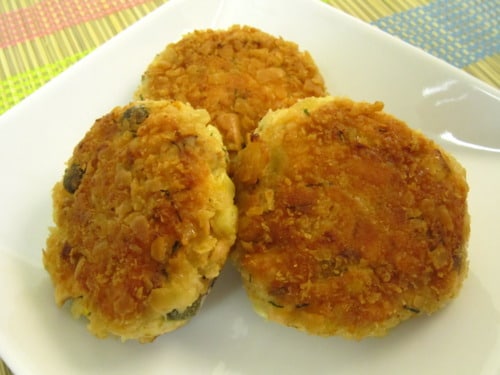 Three golden-brown salmon cakes served on a white plate.