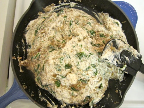 Creamy spinach and mushroom filling cooking in a skillet for lasagna roll-ups.