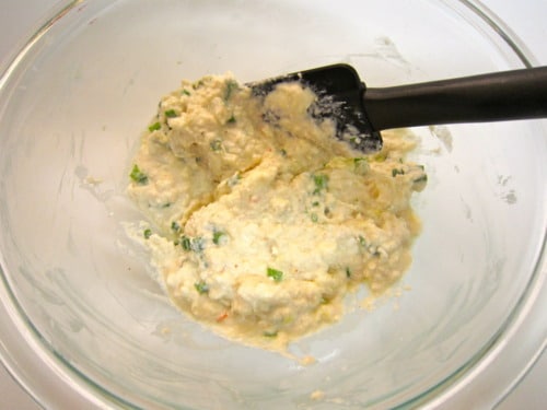 Creamy crab and cream cheese filling mixed in a glass bowl with chopped green onions, ready for wonton wrappers.