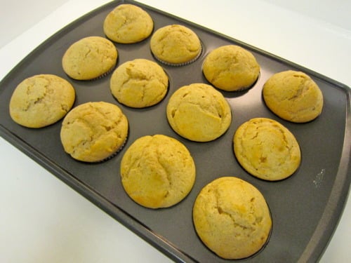 Freshly baked glazed donut muffins in a muffin tin, golden brown and ready for glazing.