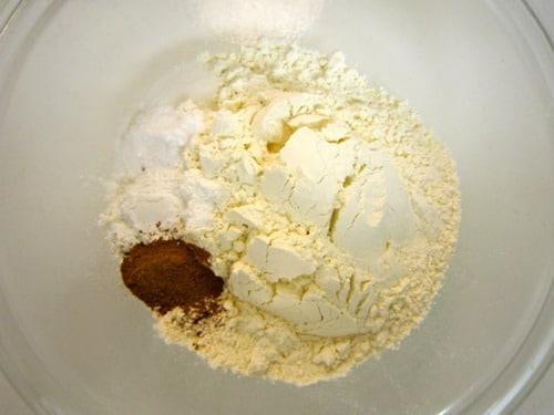 Glass bowl with flour, baking soda, salt, and ground cinnamon for pumpkin butterscotch cookies.