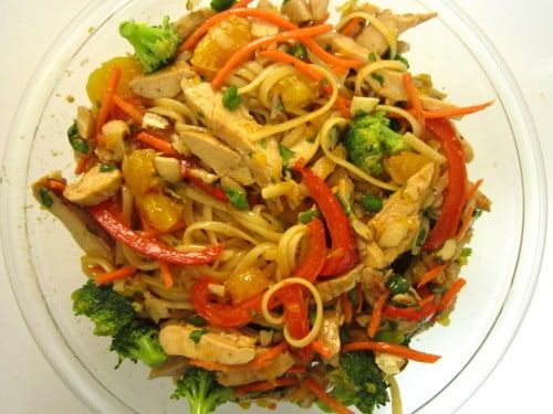 Asian chicken noodle salad with broccoli, red bell peppers, carrots, and mandarin oranges.