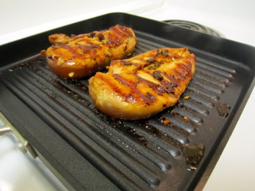 Two chicken breasts flipped on a grill