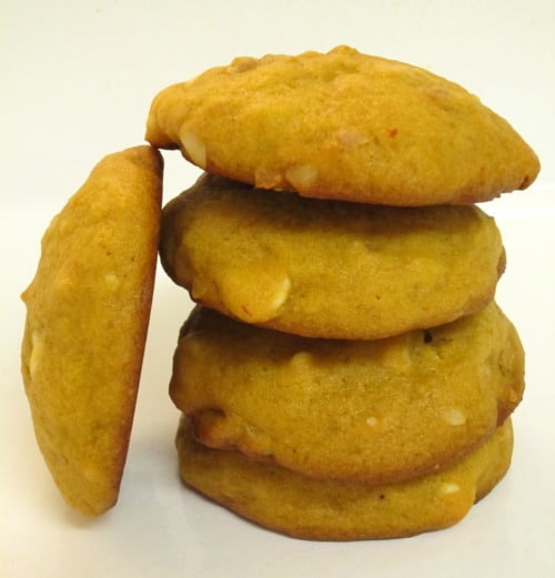 Stack of pumpkin white chocolate chip macadamia nut cookies on a white surface.