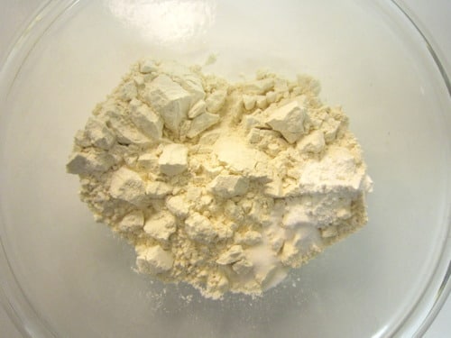 All-purpose flour in a clear glass mixing bowl, prepared as a dry ingredient for almond poppy seed bread.