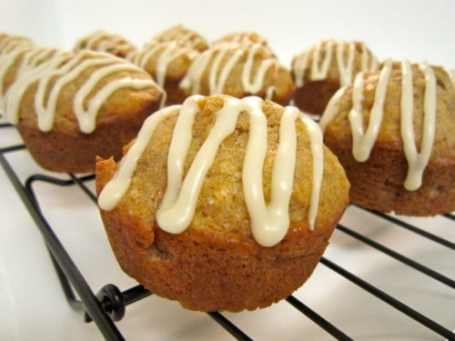Apple fritter muffins topped with vanilla glaze, cooling on a wire rack.