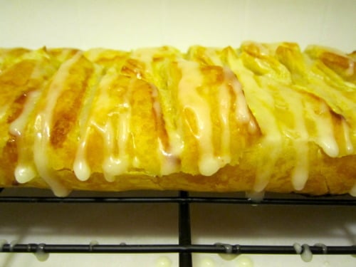 Orange cheese danish with icing glaze, cooling on a wire rack.