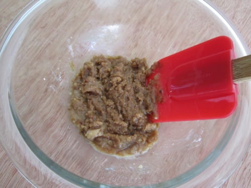 Combined flour, sugars, cinnamon, coconut oil and vanilla in a small bowl with red silicone spatula.