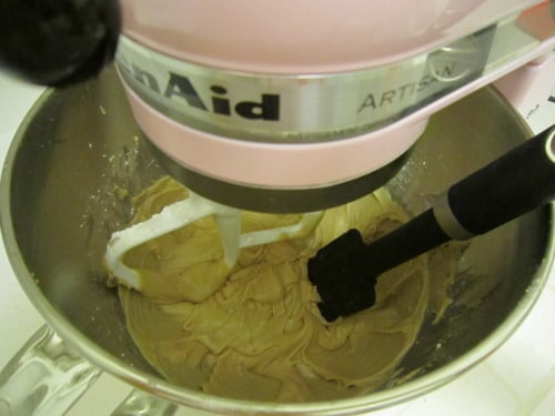 Stand mixer with paddle attachment blending cupcake batter, with a spatula resting in the bowl for Samoas cupcakes.
