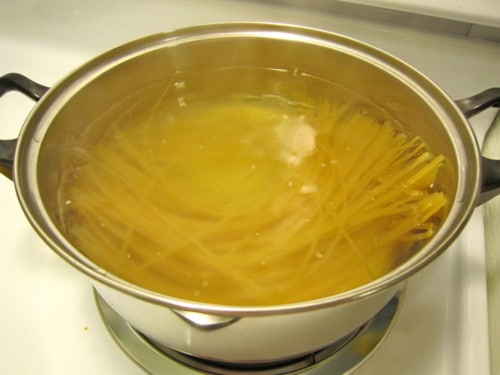 Linguini boiling in a stainless steel pot of water on the stovetop, prepared for brown butter Parmesan chicken linguini.