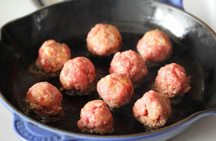 Rolled meatballs in a skillet, ready for cooking.