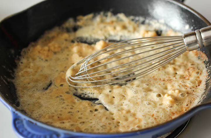 Melted butter and flour being whisked in a skillet.