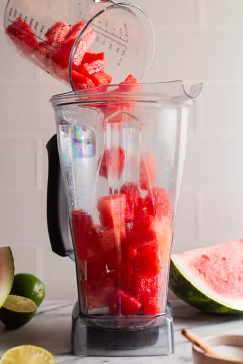 Adding watermelon chunks to a blender for slush