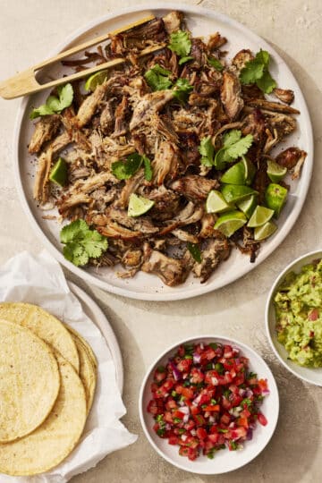 Slow cooker pork carnitas served with tortillas, guacamole, and salsa