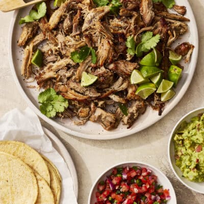 Slow cooker pork carnitas served with tortillas, guacamole, and salsa