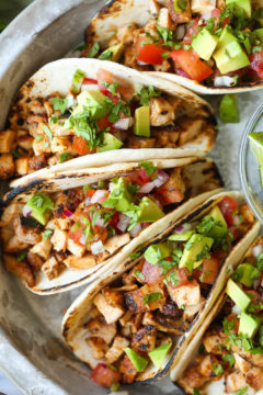 Chicken tacos recipe plated with cilantro and lime wedges