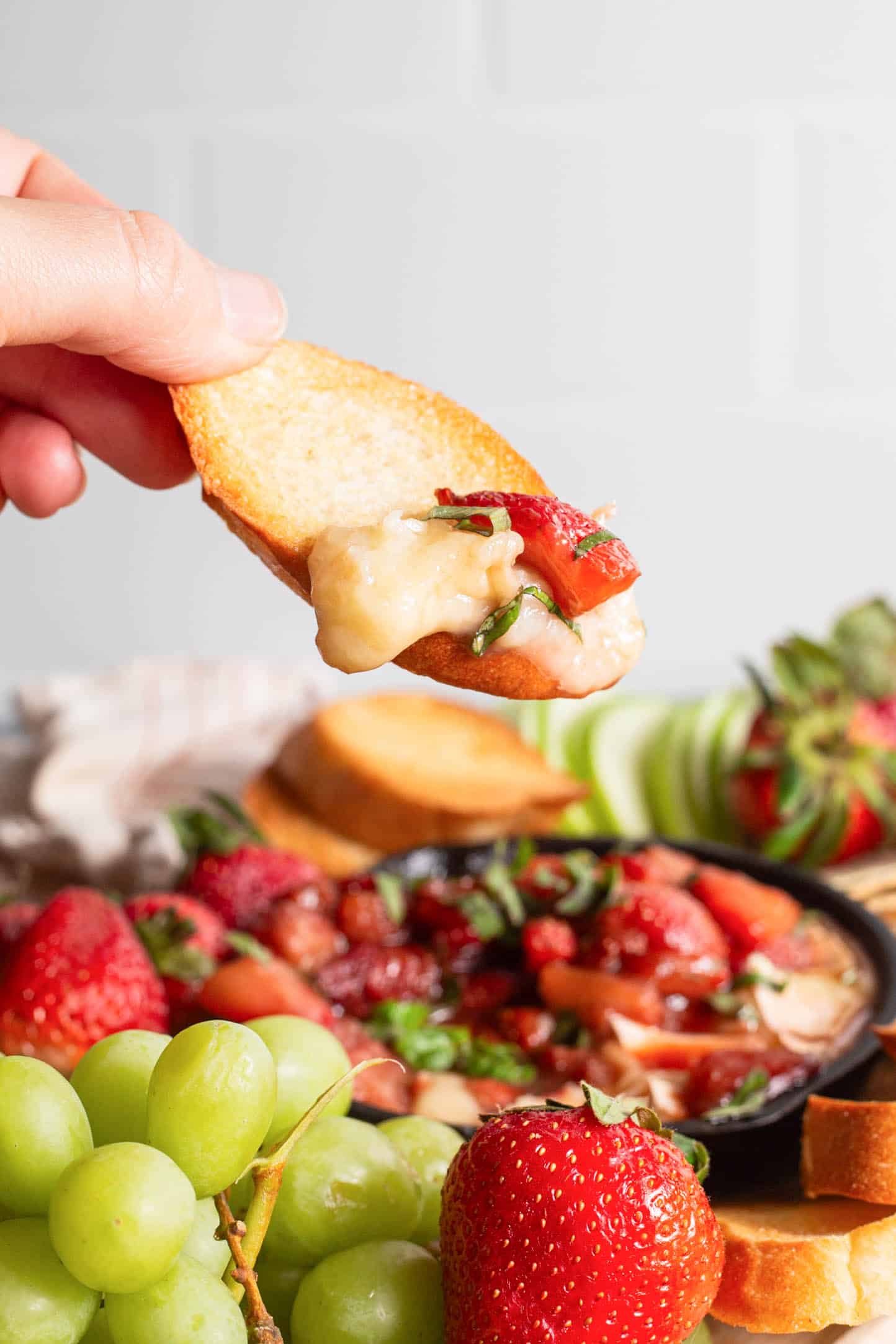Crostini dipped into strawberry baked brie appetizer