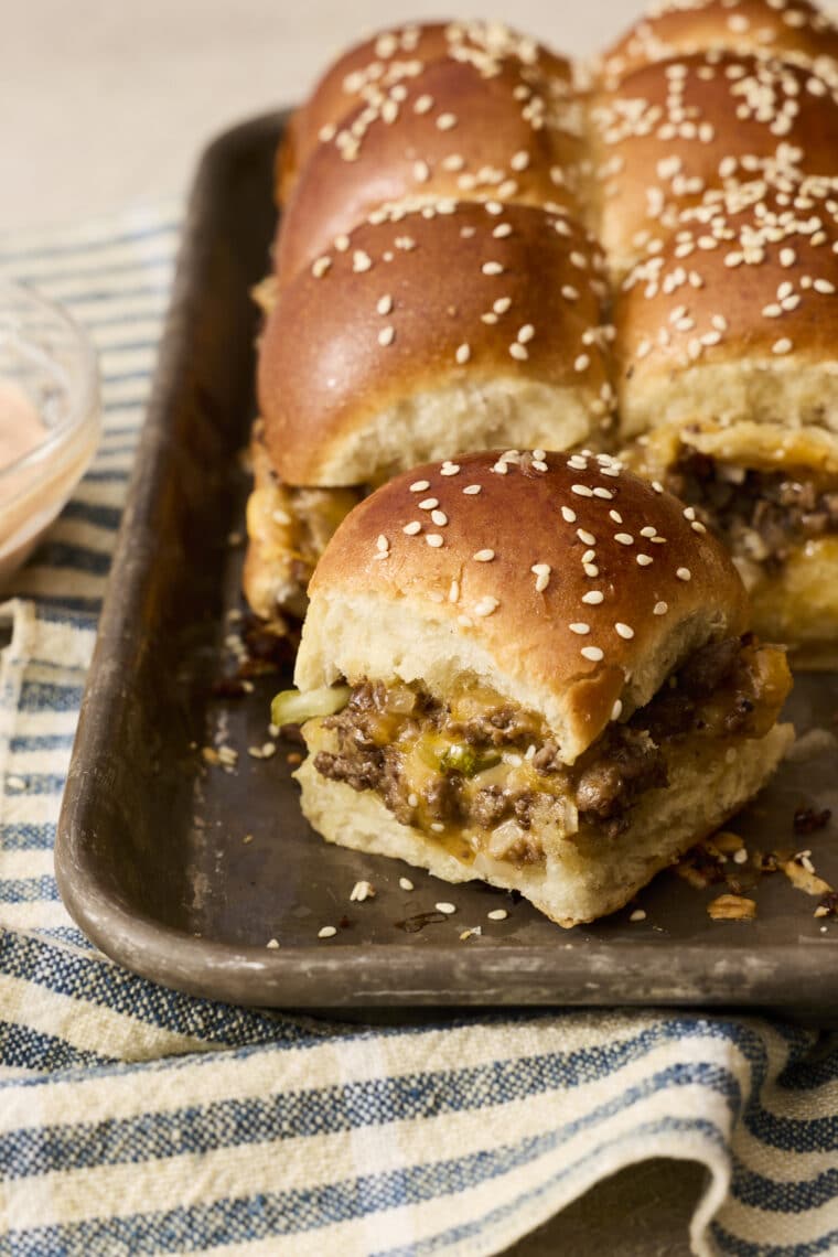 a tray of cheesy sliders on a blue and white kitchen towel